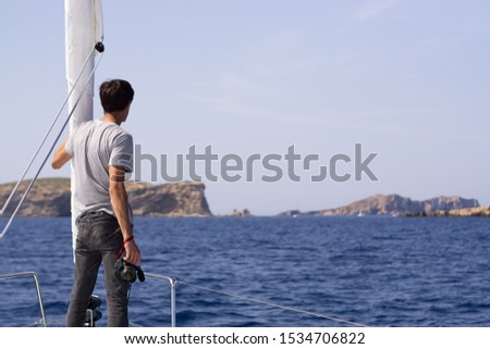 beautiful young man at the yacht vacation on the Mediterranean Sea takes some photos. Balearic Islands