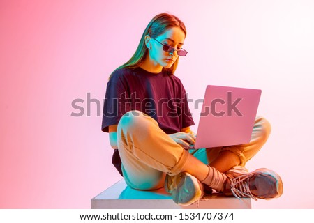 Modern Girl with laptop, tablet computer. Free creativity. Young blogger makes a Home office. Colored Neon light and background. Royalty-Free Stock Photo #1534707374
