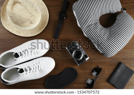 Flat lay composition with travel pillow and tourist stuff on wooden background