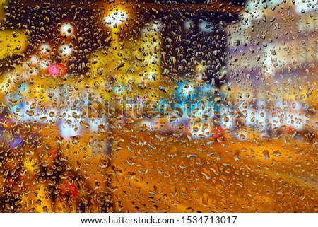 Lights of the night city. View through wet glass