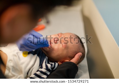 Crying little baby boy eating rotavirus vaccine at hospital. Pediatric 4 months check up. Royalty-Free Stock Photo #1534729271
