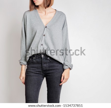 Young woman wearing simple outfit with grey button-up cardigan and black trousers isolated on light grey background. Copy space Royalty-Free Stock Photo #1534737851