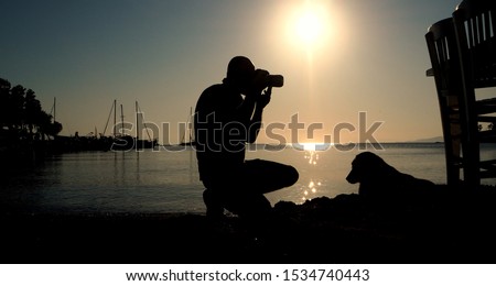 Silhouette of photographer taking photos by the sea at morning sunrise