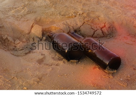 Old beer bottles on the beach. Pollution concept picture. Wastes and garbage in the sand.