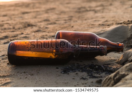 Old beer bottles on the beach. Pollution concept picture. Wastes and garbage in the sand.