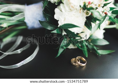 Beautiful toned picture with wedding rings against the background of a bouquet of flowers