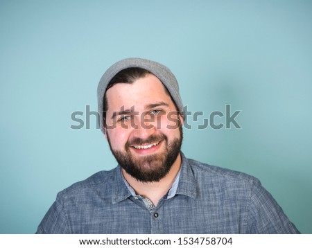 cool and young man with grey hood posing in front of blue background doing different body expressions with copy space and is happy
