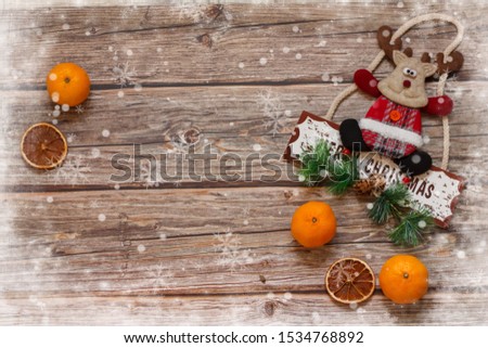 Wooden background with mandarines and Christmas deer inside the christmas hat on the table. Winter holiday frame. Flat lay top view. copy space