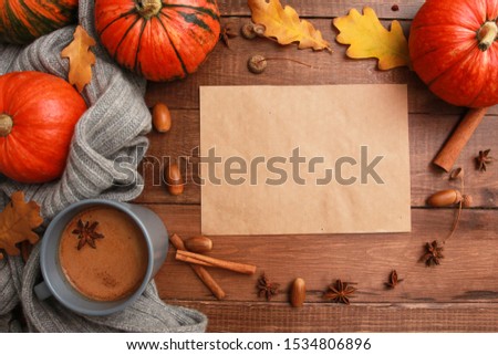 Grey cup of coffee with milk and spices, scarf, yellow oak leaves, acorns, orange pumpkins on dark brown wooden table. Welcome Autumn concept. Fall, spicy latte, thanksgiving, top, copy space