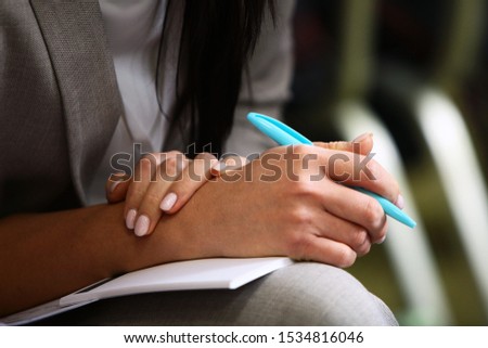 Ballpoint pen in female hands. Woman at a press conference or training. Photo without a face. Macro photo.