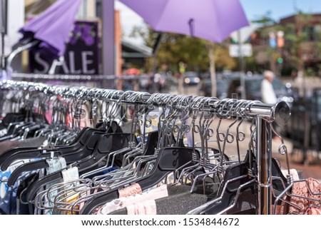 closeup of womens clothes hangers on clothes rack outside during summer sidewalk sale