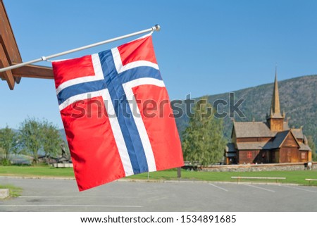 Norwegian flag and wooden church Lomskyrkja in Lom, one of the biggest stave churches in Norway dates back to 1158-59.