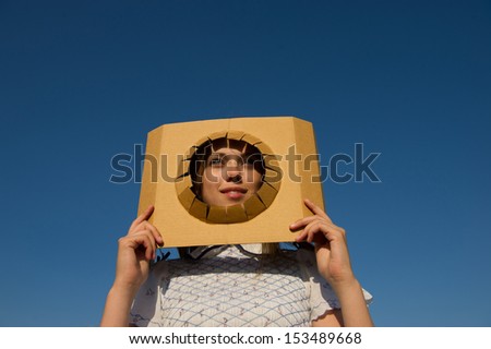 woman looks through a cutout in the paper on the background of blue sky