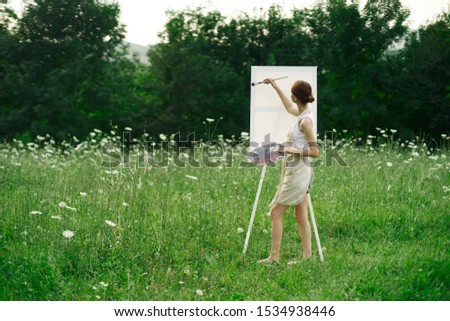 woman model paints a picture in nature