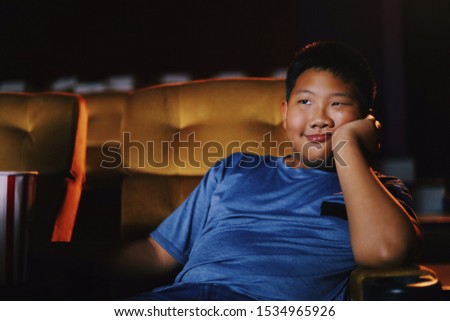 Asian boy watching movie in cinema,He’s feel boring about this movie.