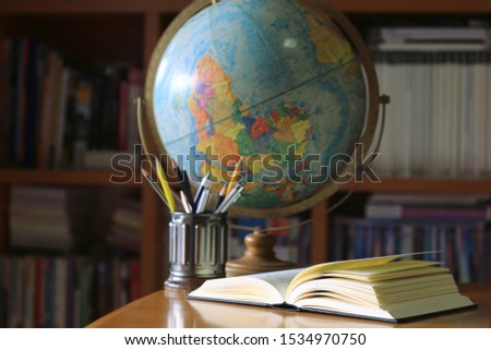 A close-up of a book opened on a library desk Bookshelf and globe in the background selective focus and shallow depth of field