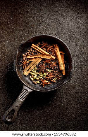 Various spices on a cast iron skillet on a dark background, top view. Christmas mulled wine aromatic spices.  