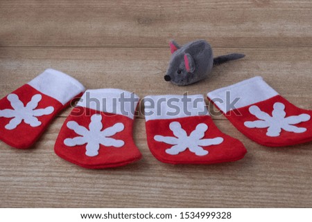 Composition of 4 toy red with snowflake boots for Christmas gifts and one rat on a wood background.