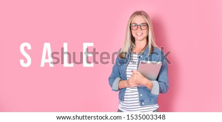 Banner with text SALE - young woman in glasses with a tablet on pink background