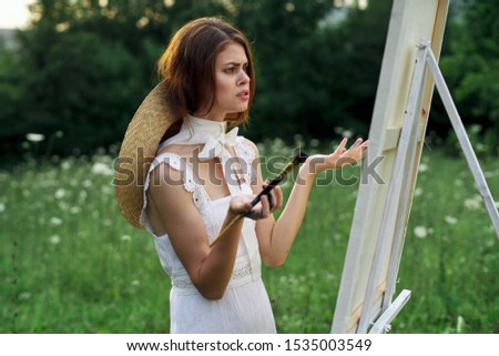 young woman on nature an easel paints with paints