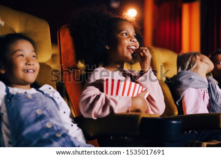 A girl eating popcorn and watching movie in cinema on weekend.