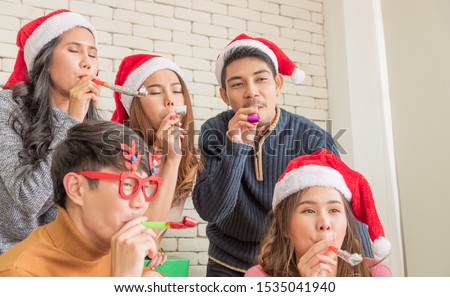 Group of young Asian man and woman in holiday winter season costume meeting together and blowing whistle in Christmas party for celebrate in holiday