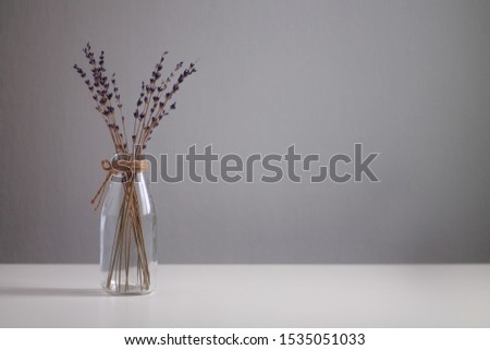 transparent vase in Scandinavian style with dried flowers purple on a light background and a white table horizontal photo