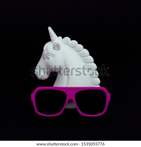 White painted unicorn and stylish sunglasses in black space. Minimal design art