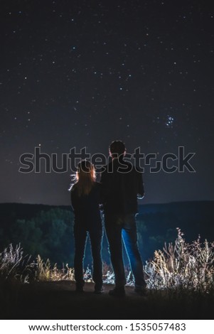 Couple, man and woman look at the sky full of stars, romantic atmosphere. travel. peak, vertical photo