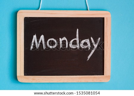 Blackboard against blue background with 'Monday' message written on it 
