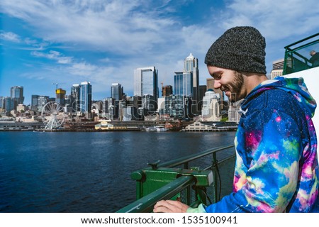 A young man standing outside on a ferry ride leaving Seattle, Washington, USA.