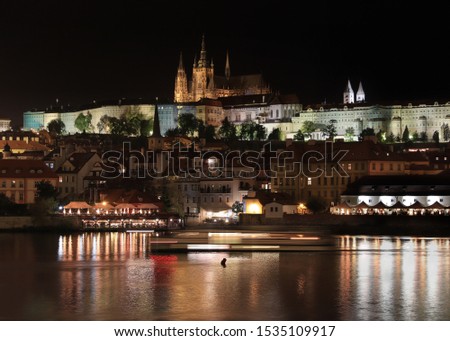 A stunning view of Prague at night, a picture taken not long before midnight, showing a river, many buildings and a famous St Vitus Cathedral from the perspective of opposite side of Charles's Bridge.