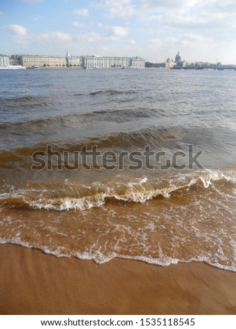 Not big waves on a sandy beach. View of the Hermitage and St. Isaac's Cathedral across the Neva river. Travel to Saint Petersburg.