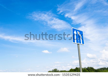 round roadsign with white arrows on blue background outdoor