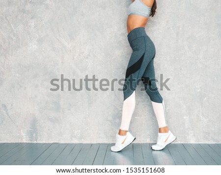 Portrait of fitness woman in sports clothing looking confident.Young female wearing sportswear. Beautiful model with perfect tanned body.Female posing in studio near gray wall Royalty-Free Stock Photo #1535151608