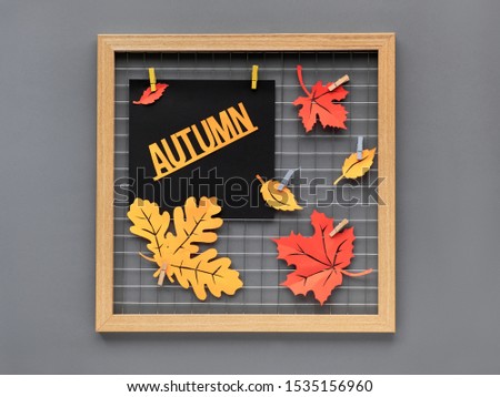 Photo grid board with red and orange paper Autumn leaves and text "Autumn". Fall paper craft concept for interior design or creative ideas for home decoration.