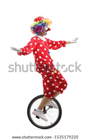 Full length profile shot of a cheerful clown riding a unicycle and making a funny grimace isolated on white background
