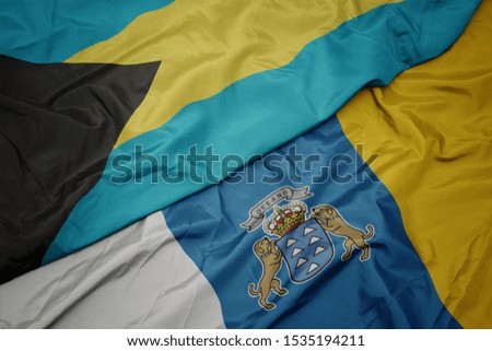 waving colorful flag of canary islands and national flag of bahamas. macro