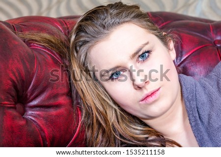 Woman is lying on the sofa and looks expressionless
