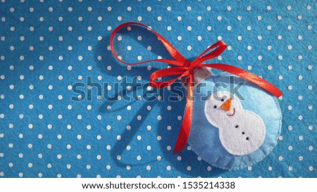 Christmas background Handmade Christmas toy lies on a blue felt with white dots. A snowman is depicted on a Christmas toy. Idea for creativity.