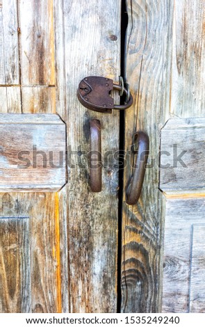 Old wooden gate with rusty padlock close up