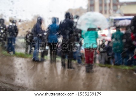 Blurred background. A crowd of people standing in the rain and snow. Autumn, winter weather.