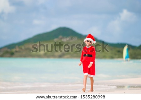 Little girl in christmas costume celebrates New Year vacation on the beach