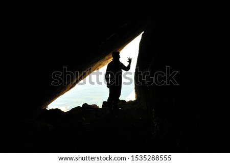 A biologist in field work, scientist, silhouette of man inside cave, reverse light, background
