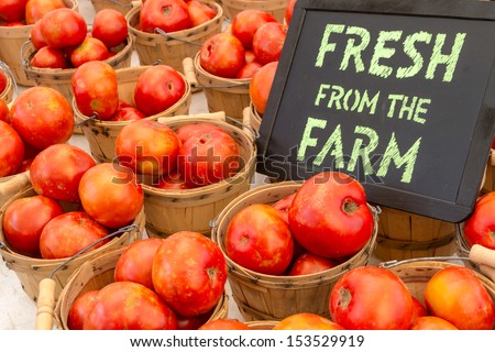 Fresh from the Farm chalk board sign display with baskets full of locally grown red tomatoes at local farmers market