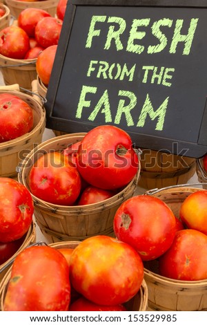 Locally grown re tomatoes for sale at local farmers market with handwritten chalk board sign