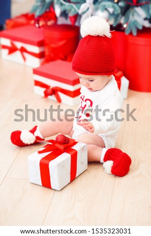 Funny infant baby girl unpacks christmas gift box. Merry Christmas and Happy New Year.