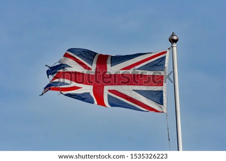 Union jack flag flying from a white flag pole with a gold cap. 