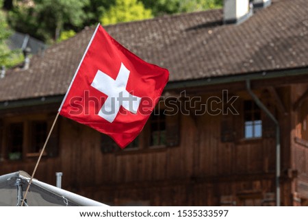 Swiss flag in front of a traditionnal mountain chalet 