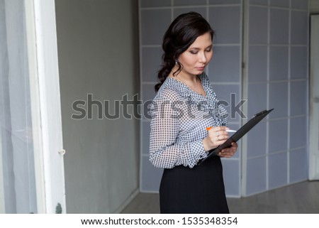 Asian woman talks on her smartphone in the office
